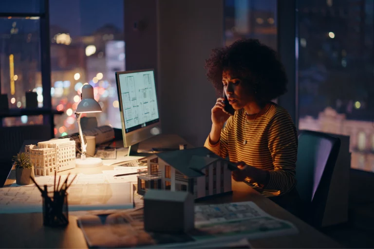 young bipoc woman sits in a modern office at night time